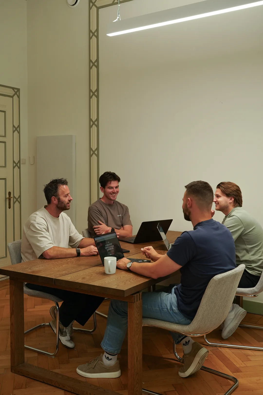 Newfive team in overleg aan tafel met laptops op kantoor